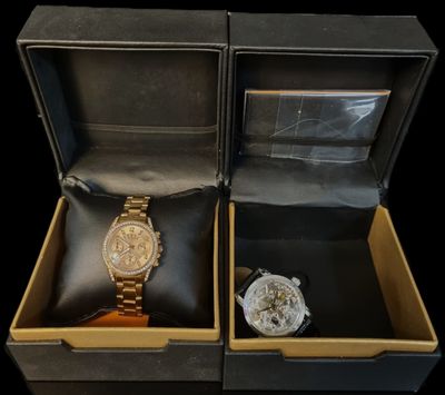 two watches sitting in a box on a black surface