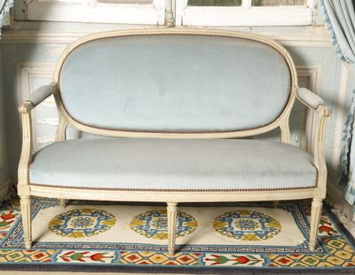 a blue couch sitting on a rug in front of a window