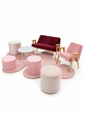 Plusieurs chaises et tabourets de différentes couleurs sont disposés autour d'une table basse