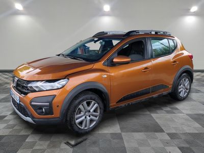 La voiture orange est garée dans une pièce dont le sol est en damier.