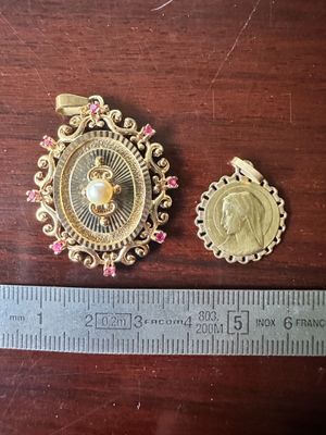 Deux pièces d'or sont posées à côté d'une règle sur une table en bois.