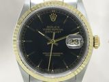 une photo d'une montre Rolex avec un cadran noir et un bracelet bicolore