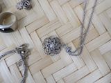 a silver necklace, ring, and bracelet on a woven table