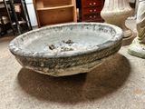 a stone bowl sitting on the floor next to a statue
