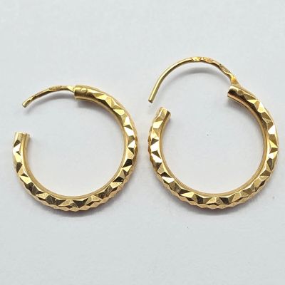 une paire de boucles d'oreilles créoles dorées sur un fond blanc