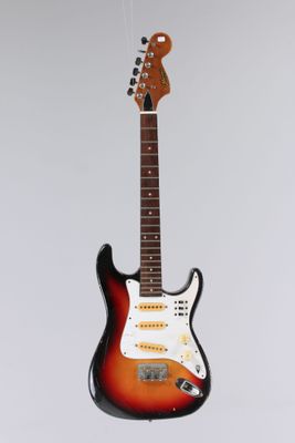 an electric guitar hanging from a string on a white wall