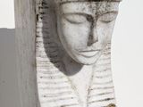 statue of a woman ' s head with a feathered hat on a white background