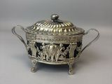 une casserole ancienne en métal argenté, ornée de motifs noirs et blancs