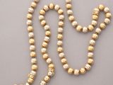 a gold beaded necklace with pearls on a gray background