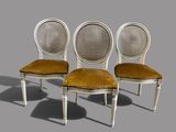 three chairs with cane back cushions and a cane back seat