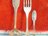 three silver spoons and two forks in a case