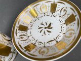 two plates with gold designs on them on a table