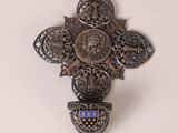 une croix accrochée au mur, sur laquelle figure un blason
