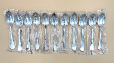 six cuillères en argent dans un sac en plastique posé sur une table