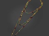 un collier composé de perles dorées, vertes et rouges sur fond noir