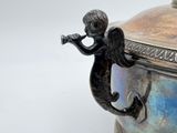 a silver vase with an angel holding a trumpet
