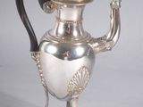 an antique silver tea pot with a black handle on a stand