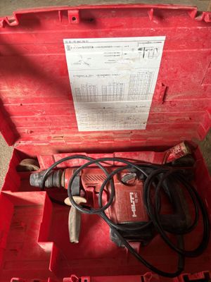 une boîte rouge contenant une perceuse et une cordelette