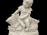 statue d'un garçon assis sur une pile de livres, tenant un panier