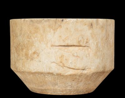 a stone bowl with a face carved into it