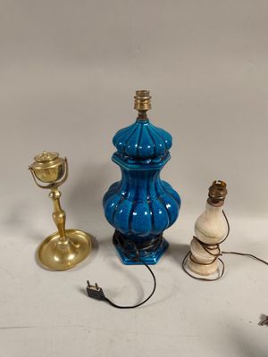 un vase bleu et une bougie dorée posés sur une table blanche