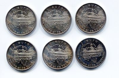 six pièces de 25 cents canadiennes sont disposées en rangée sur une surface blanche