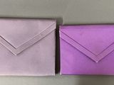 two folded envelopes are sitting on a table next to each other