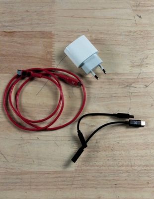 a red and white cord connected to a charger on a wooden table