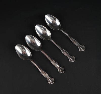 four silver spoons on a black surface with a black background