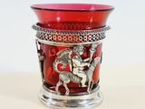 a red glass vase with a silver decoration on it
