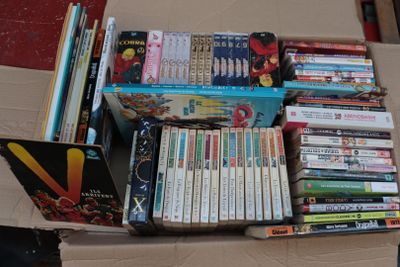 a cardboard box filled with books and dvds