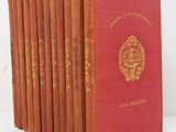 six livres rouges sont alignés sur une surface blanche
