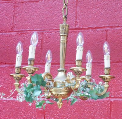 un lustre doré orné de feuilles vertes et de bougies suspendues