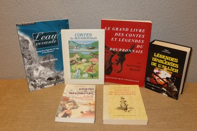 several books are sitting on a table in front of a wall