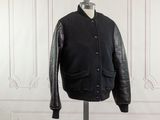 a black jacket on a mannequin stand in front of a white wall
