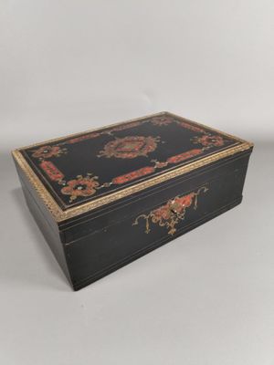 une boîte noire et dorée ornée d'un motif floral sur le couvercle