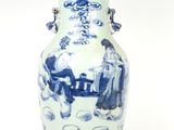 un vase bleu et blanc posé sur un socle, sur une surface blanche