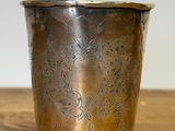 a silver cup on a wooden table with a white background