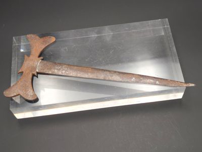 un objet métallique muni d'un manche en bois posé sur une surface claire
