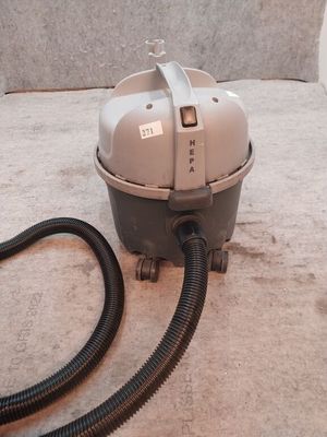 un aspirateur posé sur le sol à côté d'un tuyau
