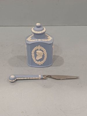 un petit pot bleu et blanc, avec un couteau à côté