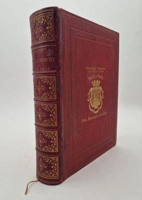 an old red book with gold trim sitting on top of a white surface