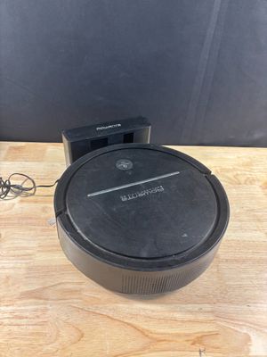un aspirateur robot noir posé sur une table en bois