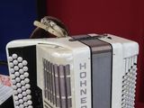 a white accordion sitting on a red table next to a black case