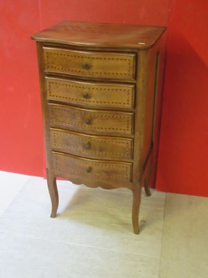 a small wooden chest of drawers against a red wall