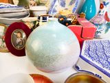 a table with a vase, plates, bowls, and pictures on it