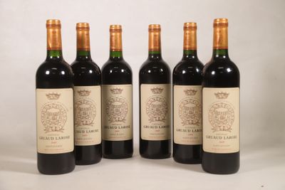 quatre bouteilles de vin sont alignées sur une surface blanche