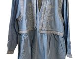 une image représentant une chemise bleue ornée de broderies blanches
