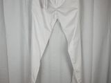 the white pants are hanging on a hanger in front of a curtain