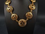 a gold necklace on a mannequin display with a black background